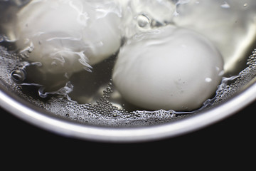 chicken eggs boil in water.  eggs are cooked in a saucepan on the stove.