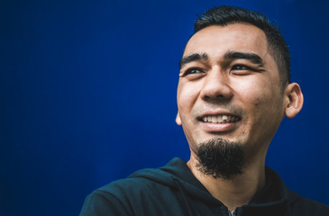 Obraz premium Closeup shot of happy young man smiling in blue background