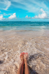 Woman's feet on the tropical Caribbean beach. Ocean and blue sky