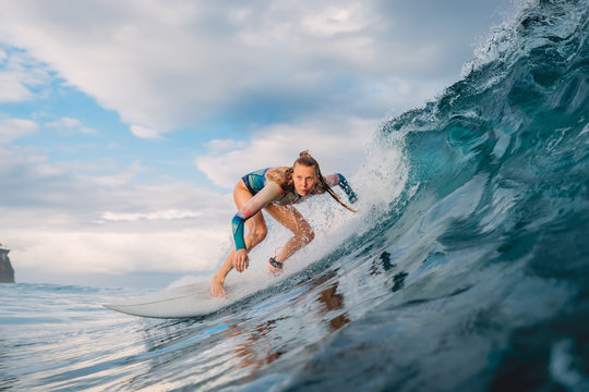 Beautiful surfer girl on surfboard. Woman in ocean during surfing. Surfer and barrel wave