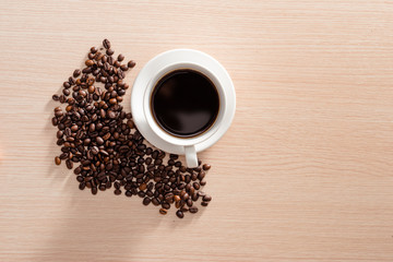 Coffee cup with coffee beans on wooden background