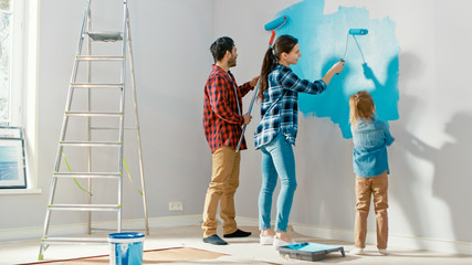 Family Time Together with Small Daughter. Young Father and Mother Showing Their Child How to Paint...