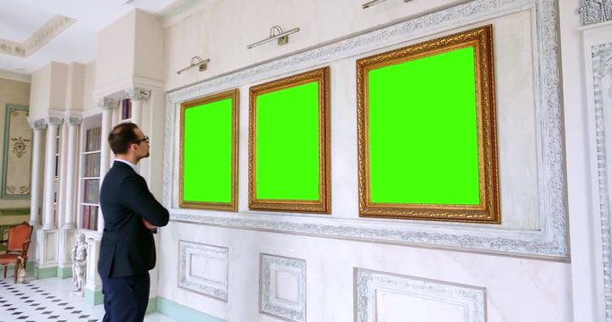 young caucasian man in an art gallery looking at paintings