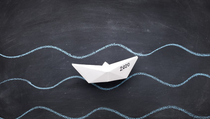 White origami boat with 2020 sailing by river