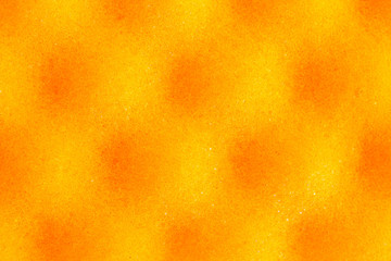 Yellow spotted background with round black spots. The pattern on the surface of the sponge porous material. Pores of the material under high magnification. Microscale, macrophotography.