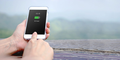 Female hand holding mobile phone with charged battery on screen