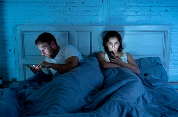 Fototapeta na wymiar Couple in bed having relationship communication problems suffering from internet mobile addiction.
