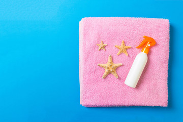 Summer beach flat lay accessories. Sunscreen bottle cream, towel and seashells on colored Background. Travel holiday concept with copy space