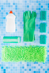 Colorful cleaning set for different surfaces in kitchen, bathroom and other rooms on kitchen mosaic surface background. Top view of cleaning service concept.