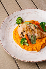 Chicken breast steak with carrot puree baby carrot and broccoli. Grilled chicken slice with baby carrot puree. wooden backgrounf