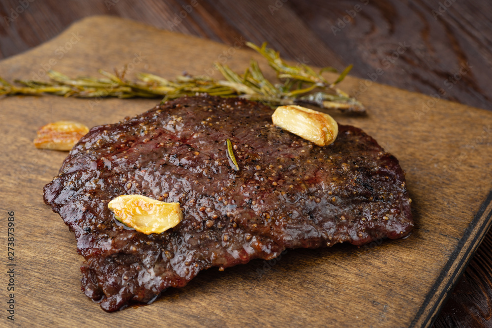 Wall mural beef steak with twig rosemary on a wooden table.