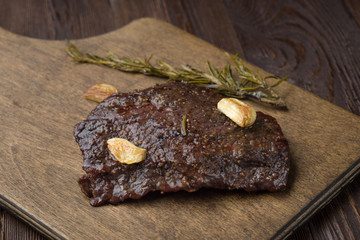 Beef steak with twig rosemary on a wooden table.