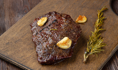 Beef steak with twig rosemary on a wooden table.