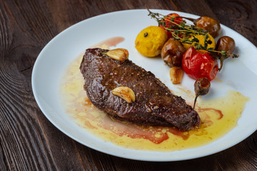Rib-eye steak with baked vegetables resting on a white plate