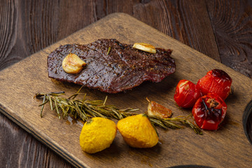 Grilled rib eye  steak with spices  served on a wooden board with baked vegetables