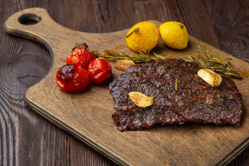 Grilled rib eye  steak with spices  served on a wooden board with baked vegetables