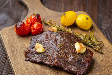 Grilled rib eye  steak with spices  served on a wooden board with baked vegetables