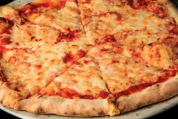 top view of whole sliced cheese pizza on round white plate