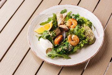 Healthy Salad. Recipe for fresh seafood. Grilled shrimps, mussels and squid, fresh salad lettuce and avocado puree. Healthy Eating. Wooden background