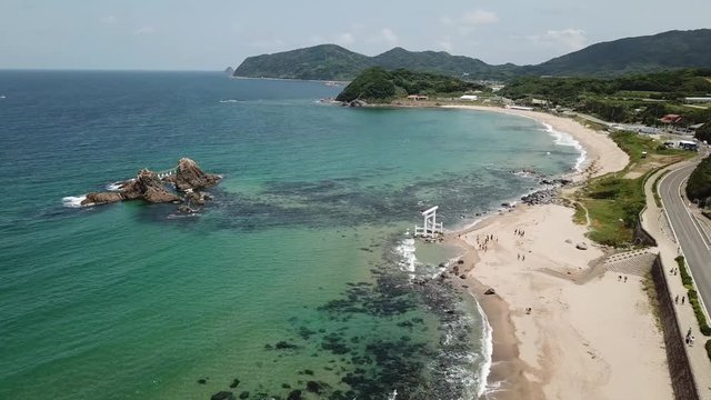 aerial footage of blue ocean, the twin rocks and the white torii gate on the water at the coast of sakurai futamigaura beach, itoshima fukuoka japan, poi v07