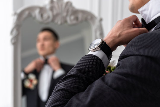 The Man Looks In The Mirror And Straightens His Bow Tie. Wristwatch In Focus Close-up. Selective Focus