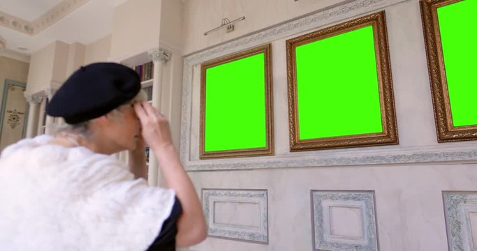 Elderly woman putting on glasses to observe art pieces