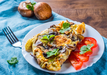 omelette with mushrooms in white plate on wooden table background