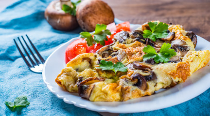 omelette with mushrooms in white plate on wooden table background