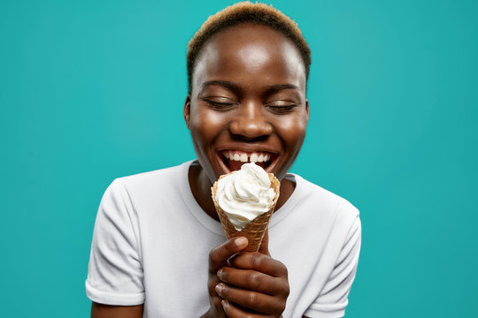 Happy african girl holding waffle horn with white ice cream.