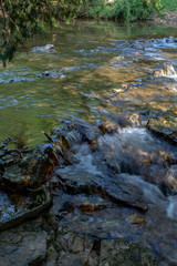 Fototapeta premium After heavy rains this little creek in southwest Missouri make a pretty scene with a little waterfall. The photographer captured a bokeh effect and creamy flowing waters.