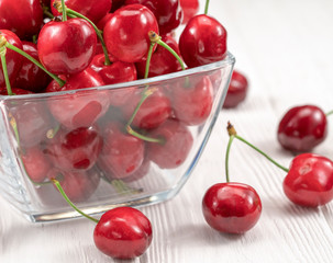 Ripe Cherries In A Wicker Plate On A White Wooden Background.