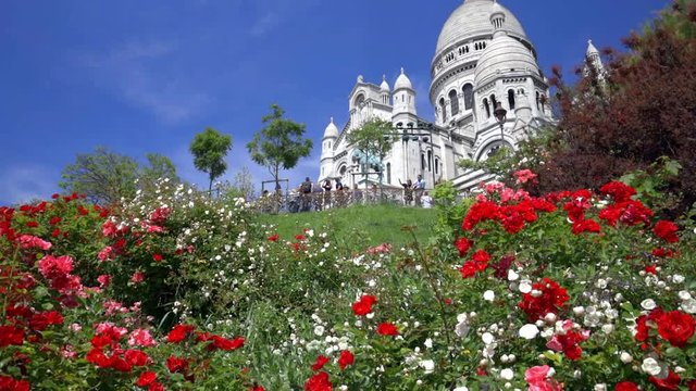 Basilica of the Sacr&eacute;-Coeur, also known as the Sacred Heart, the famous church in Montmartre in Paris France on a spring day with a blue sky nestled on the hill surrounded with green grass and flowers