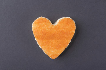 Obraz premium Dessert with a crispy golden crust in the shape of a heart on a plate with a blue border with a wooden fork and spoon