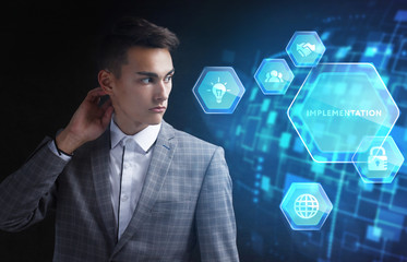 The concept of business, technology, the Internet and the network. A young entrepreneur working on a virtual screen of the future and sees the inscription: Implementation