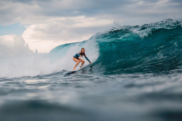 Surf girl on surfboard. Surfer woman and big blue wave