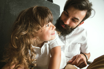 Father playing with young son in their sitting room at home. Young dad having fun with his children in holidays or weekend. Concept of parenthood, childhood, father's day and family relationship.