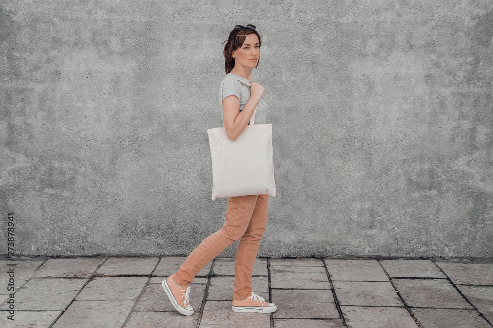 Wall mural Young woman with white cotton bag in her hands. Mock up.