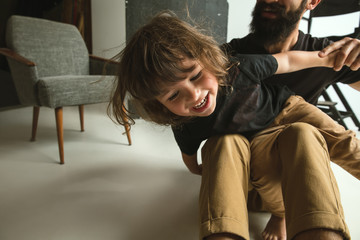 Father playing with young son in their sitting room at home. Young dad having fun with his children in holidays or weekend. Concept of parenthood, childhood, father's day and family relationship.
