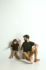 Father playing with young son against white studio background. Young dad having fun with his children in holidays or weekend. Concept of parenthood, childhood, father's day and family relationship.