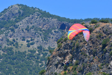 Paragliding. Paragliders on a blue sky and mountains background.