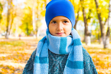 portrait of a brown-eyed boy in a hat and a large knitted scarf in autumn