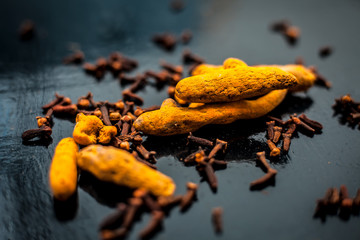 Face mask or pack’s ingredients on wooden surface for acne which are turmeric or haldi and cloves. Ingredients spread on the surface. Horizontal shot.