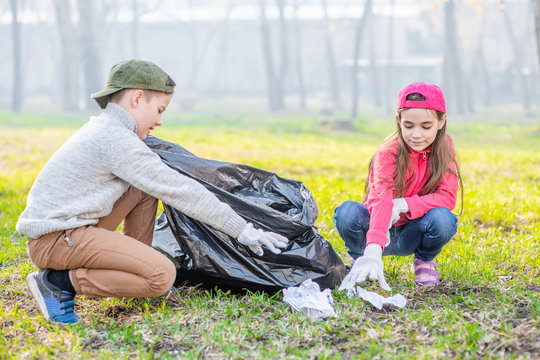 Happy kids scavenge trash in the spring park. Volunteer and ecology concept