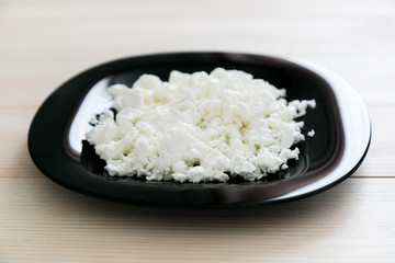 Cottage cheese on a black glass plate. Delicious and healthy breakfast milk cottage cheese