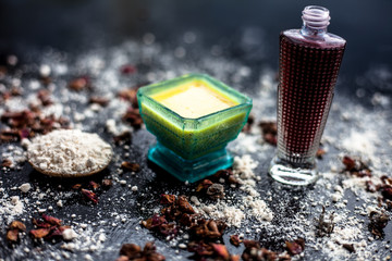 Face mask for skin whitening on wooden surface consisting of besan or gram flour and some rose water. With some dried rose petals and gram flour spread on the surface. Horizontal shot.