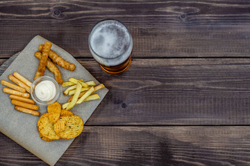 Diverse snacks with beer on dark wooden background. Top view, Empty space for text