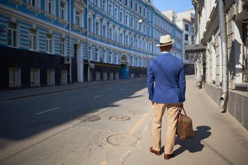 Back view of a man in a jacket and hat on the street      