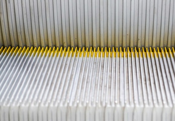 Escalator in the basement. Step up the escalator staircase. Yellow bars, steel bars, yellow iron bars