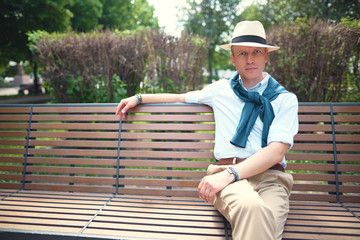Fototapeta premium Portrait of a guy sitting on a park bench