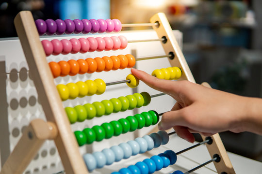 Male hand calculating with beads on wooden rainbow abacus for number calculation. Mathematics learning concept